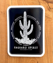 Load image into Gallery viewer, Saguaro Spirit Sticker 2.55&quot; wide by 3.5&quot; in height displayed on wood for contrast. Design is white on a black background with rounded corners.  Each vinyl sticker has an easy peel backing with a standard gloss finish.
